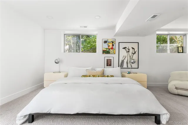 a bedroom with a bed a painting on the wall and a window