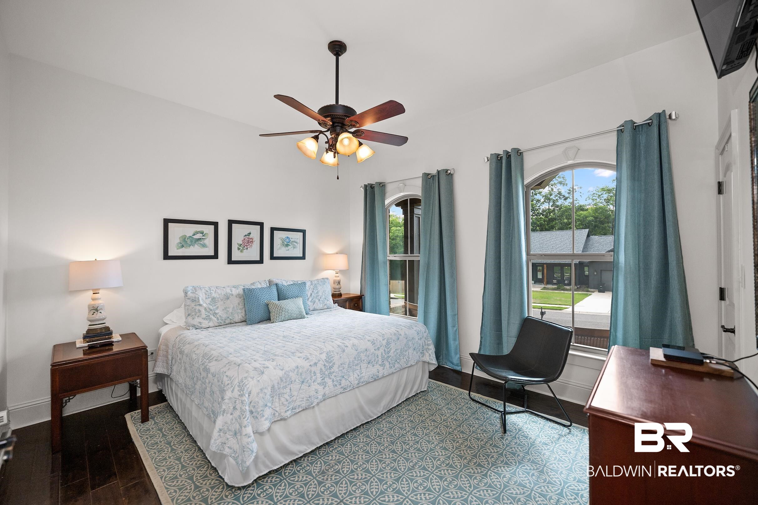 313 Pecan Ridge Boulevard Fairhope, AL 36532 - Photo 17 of 51 Bedroom featuring arched windows, dark wood-finish flooring, a ceiling fan with integrated lighting, and white walls