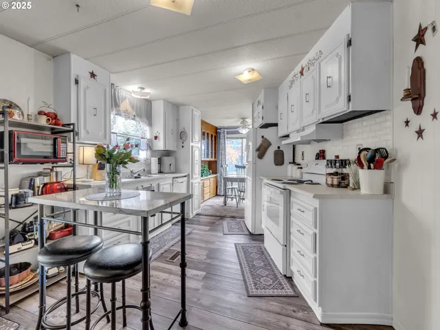 a kitchen with stainless steel appliances kitchen island granite countertop a dining table chairs sink and cabinets