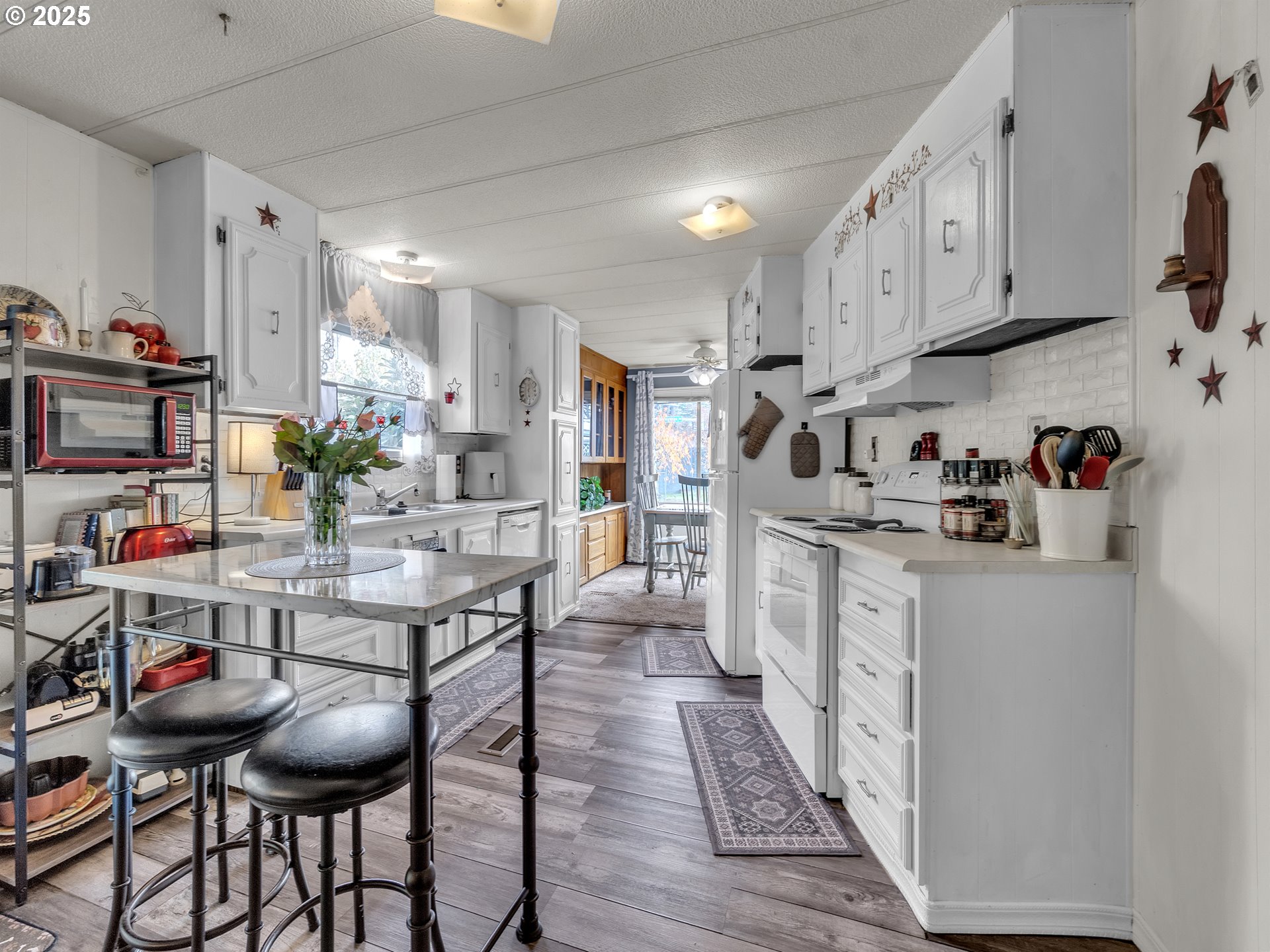2902 East 2nd Street, Unit 98 Newberg, OR 97132 - Photo 9 of 25 a kitchen with stainless steel appliances kitchen island granite countertop a dining table chairs sink and cabinets