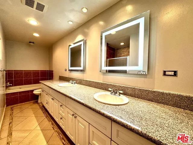 a bathroom with a granite countertop double vanity sink and mirror