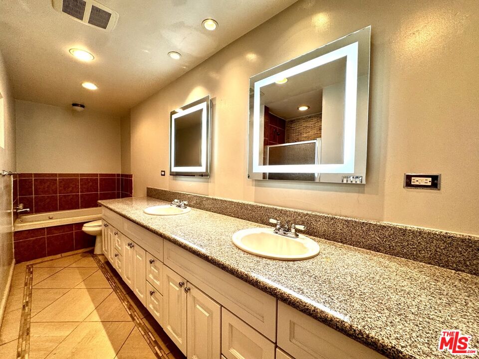 8455 Fountain Avenue, Unit 412 West Hollywood, CA 90069 - Photo 13 of 21 a bathroom with a granite countertop double vanity sink and mirror