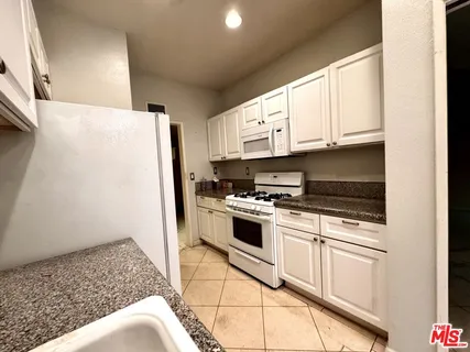 a kitchen with stainless steel appliances granite countertop a refrigerator sink and stove