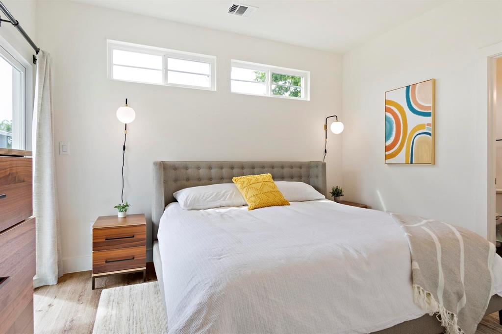 911 Stobaugh Street, Unit 2 Austin, TX 78757 - Photo 18 of 26 Bedroom featuring light wood-finish flooring, white walls, and a tufted upholstered headboard