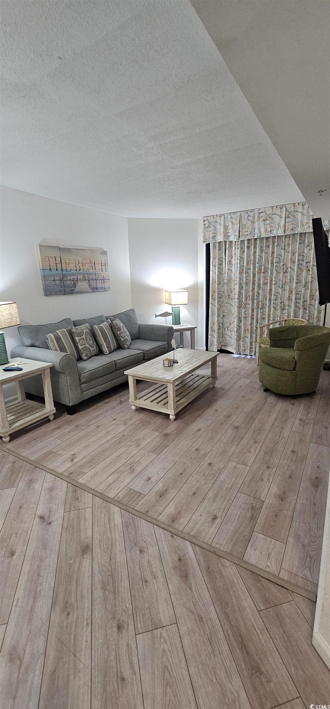 7100 North Ocean Boulevard, Unit 724 Myrtle Beach, SC 29572 - Photo 5 of 16 Living area featuring light wood-style floors and a textured ceiling