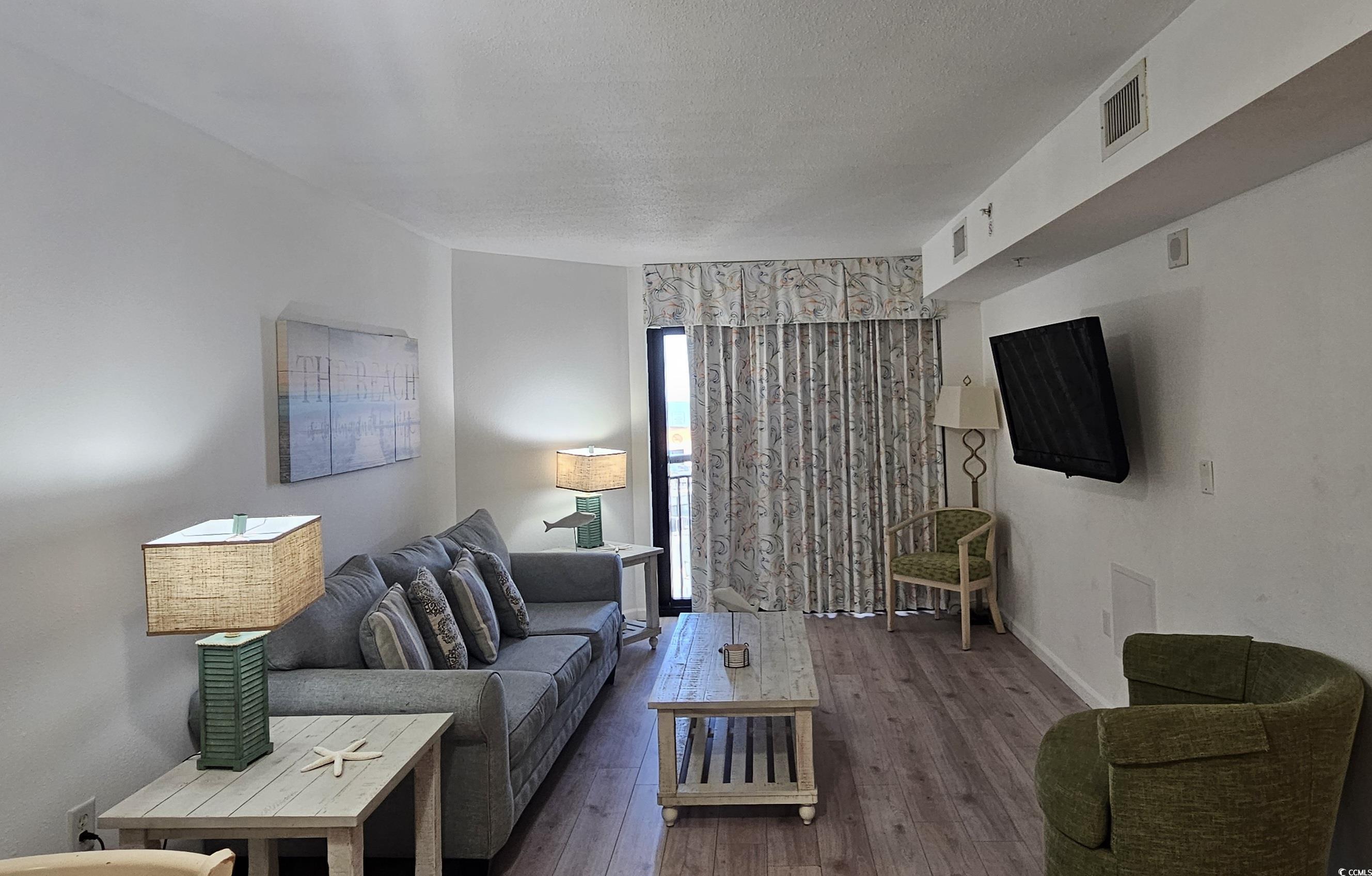 7100 North Ocean Boulevard, Unit 724 Myrtle Beach, SC 29572 - Photo 7 of 16 Living room featuring hardwood / wood-style flooring and a textured ceiling