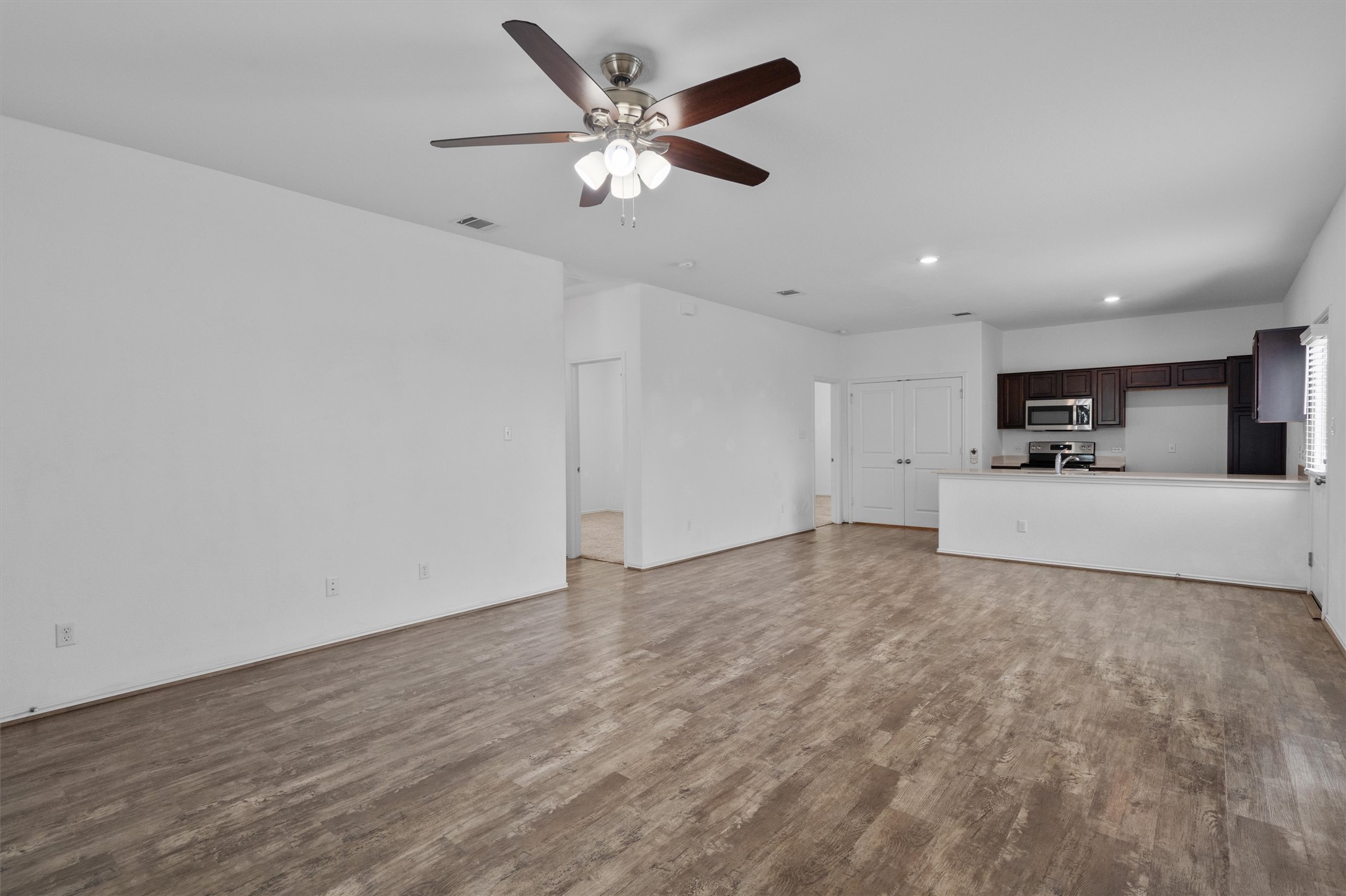 791 Circle Way Jarrell, TX 76537 - Photo 7 of 36 Open concept living space featuring wood-finish flooring, a ceiling fan with integrated lighting, and white walls