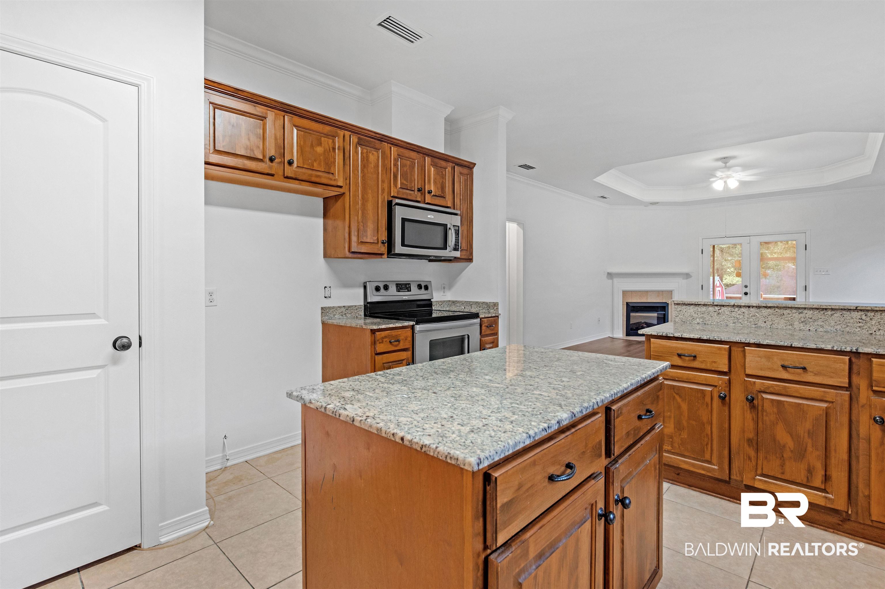 1007 Linlen Avenue Mobile, AL 36609 - Photo 9 of 21 Kitchen with a center island, a tile fireplace, ceiling fan, light stone countertops, and appliances with stainless steel finishes