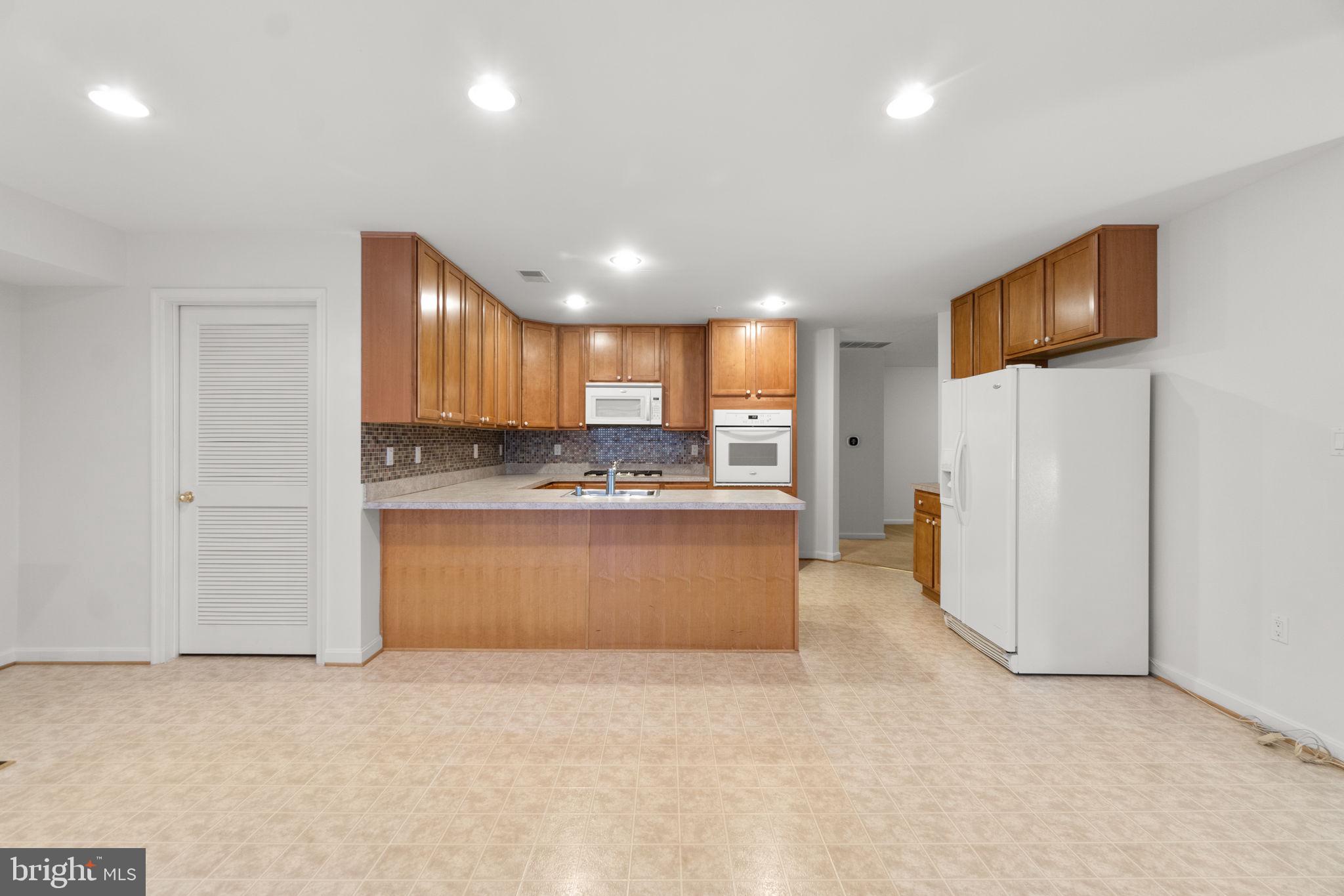 9510 Coyle Road, Unit 109 Owings Mills, MD 21117 - Photo 11 of 41 a large kitchen with a refrigerator a stove top oven a sink and cabinets