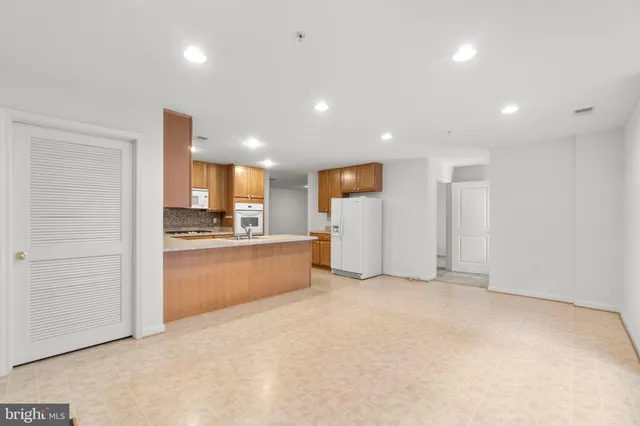 a view of an empty room and a kitchen