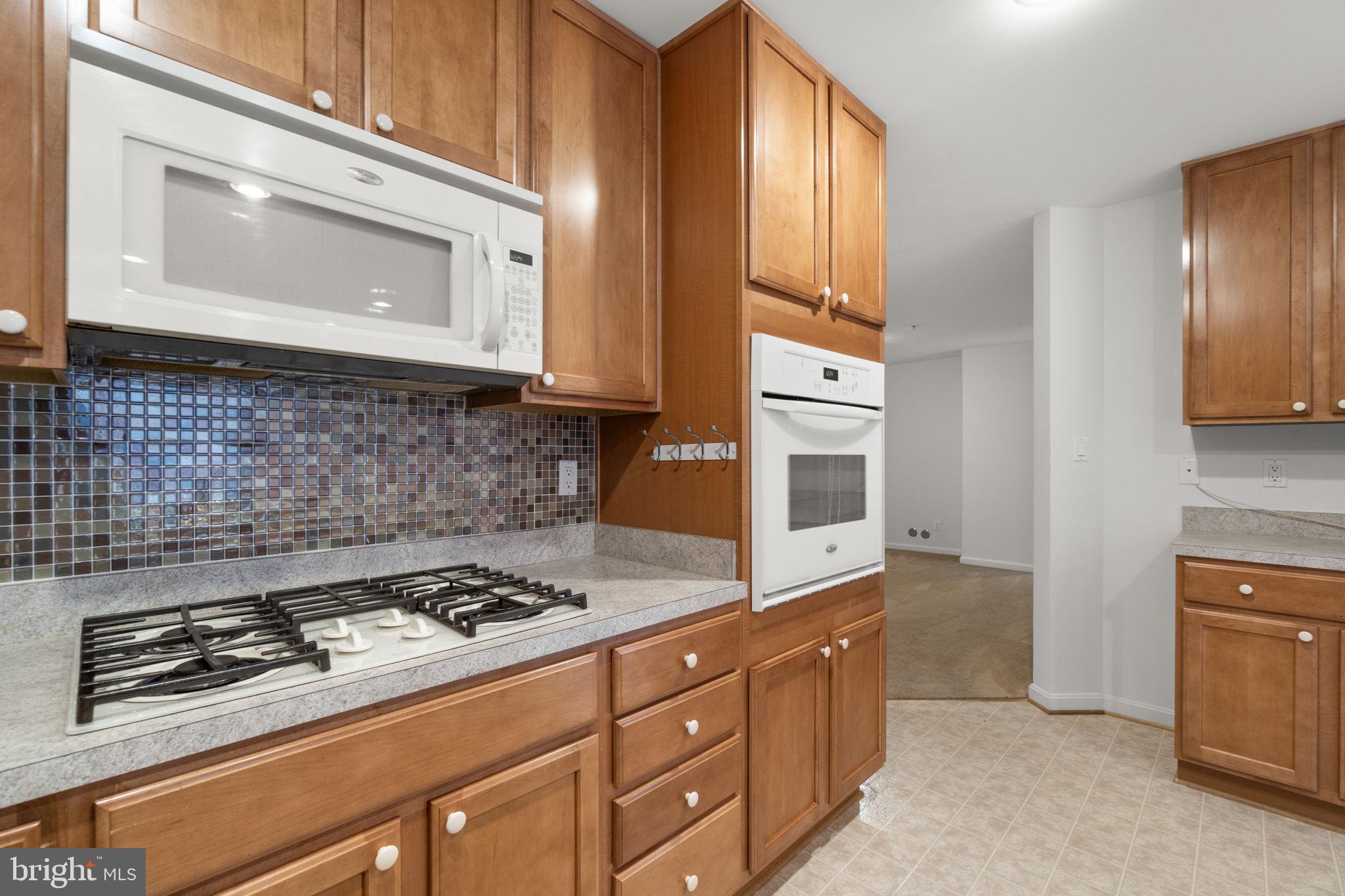 9510 Coyle Road, Unit 109 Owings Mills, MD 21117 - Photo 19 of 41 a kitchen with stainless steel appliances granite countertop a stove a microwave and cabinets