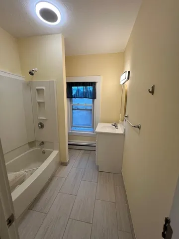 a bathroom with a tub sink and mirror