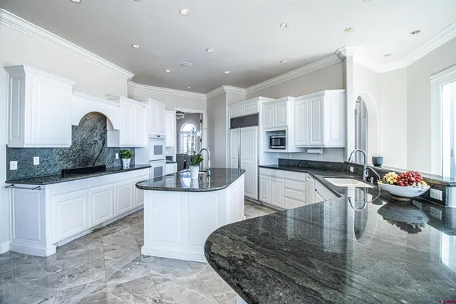 a large white kitchen with lots of counter space and chandelier