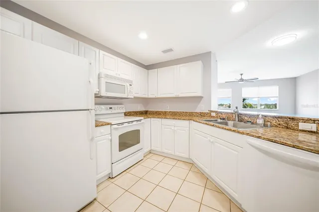 a kitchen with granite countertop white cabinets and white appliances