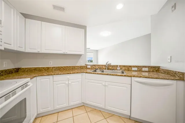 a kitchen with granite countertop white cabinets and white appliances