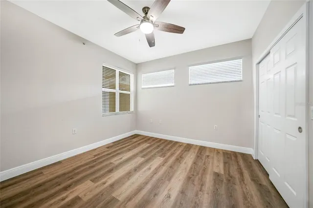 a view of empty room with wooden floor and fan