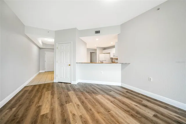 a view of a room with wooden floor and kitchen view
