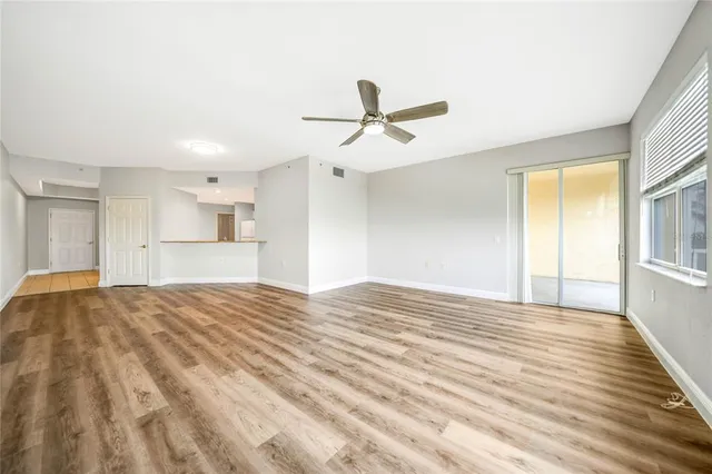 a view of empty room with wooden floor and ceiling fan