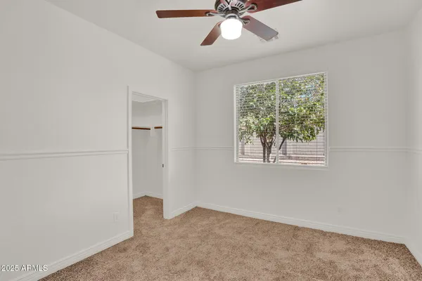 an empty room with a window and a fan