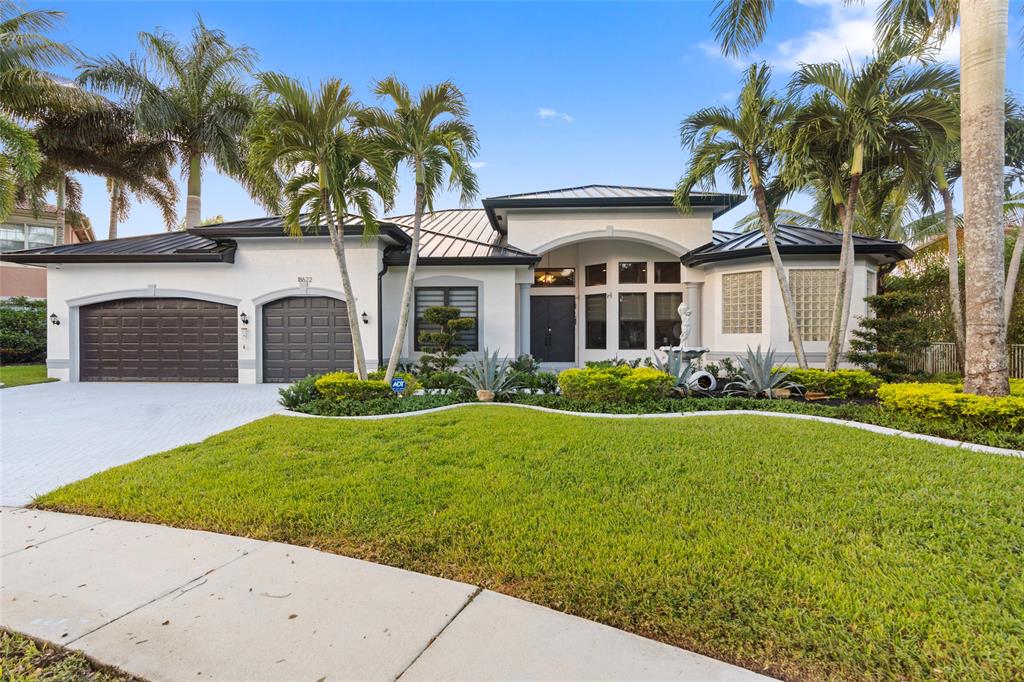 a front view of a house with a garden and palm trees