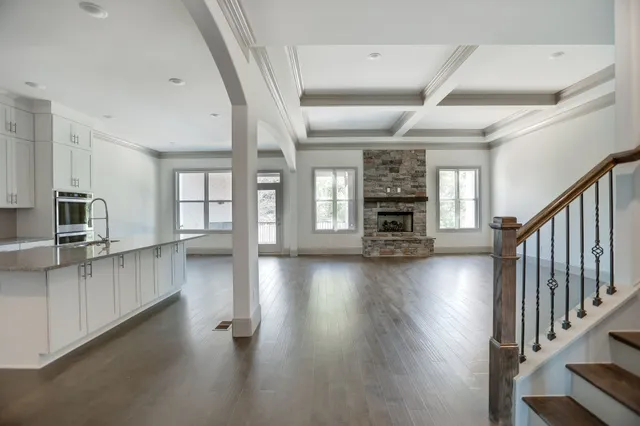 an empty room with wooden floor fire place and windows