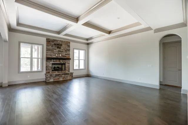 an empty room with fireplace wooden floor and windows