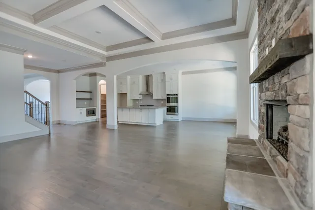 a view of empty room with wooden floor and kitchen view