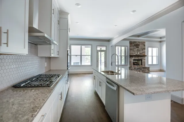 a large kitchen with a center island wooden floor and stainless steel appliances