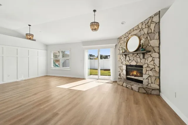 a view of an empty room with wooden floor fireplace and a window