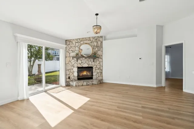 a view of an empty room with wooden floor fireplace and a window