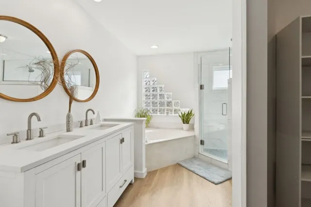 a bathroom with a double vanity sink mirror and bathtub