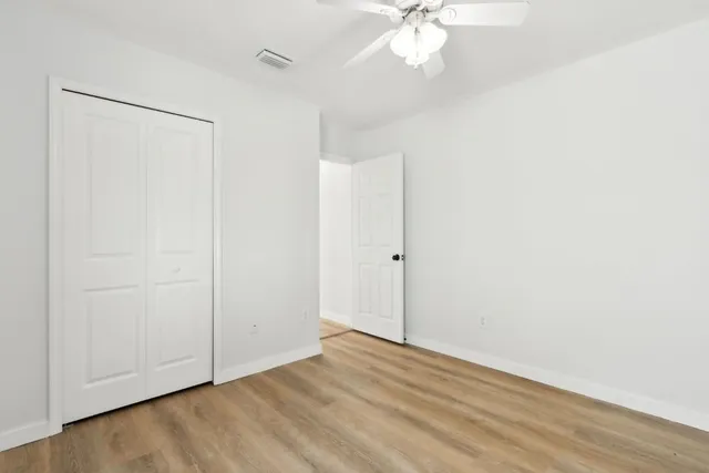 an empty room with wooden floor and fan