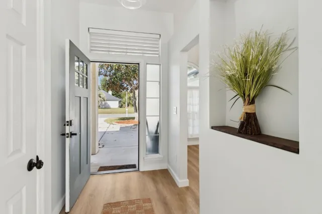 a view of a hallway with wooden floor and a potted plant