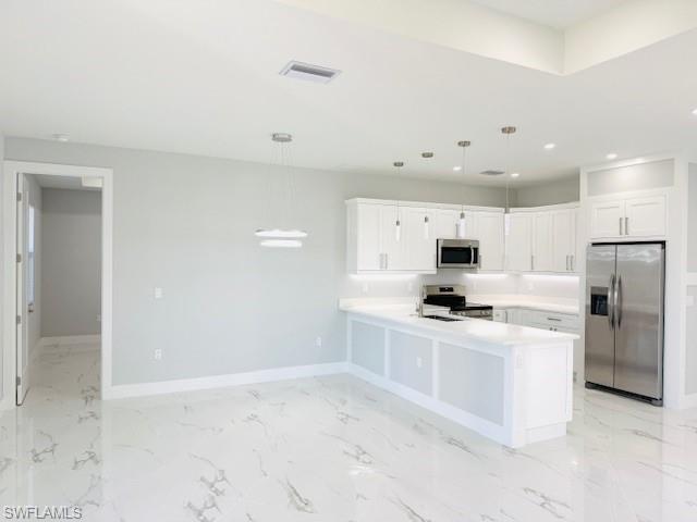 165 Patio Street Lehigh Acres, FL 33974 - Photo 21 of 34 Kitchen featuring appliances with stainless steel finishes, light countertops, a peninsula, white cabinets, and pendant lighting