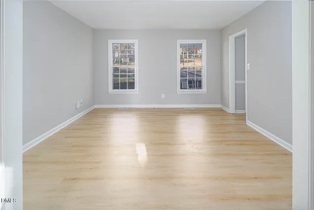 a view of an empty room with wooden floor and windows