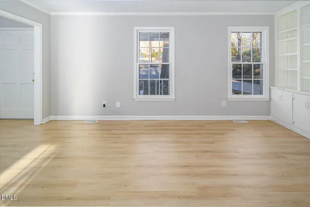 a view of an empty room with wooden floor and a window