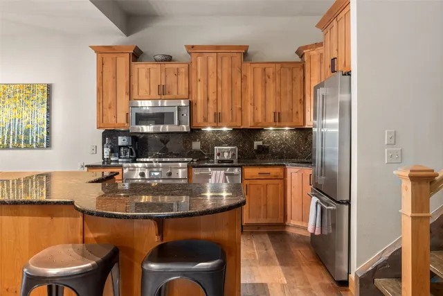 a kitchen with stainless steel appliances granite countertop a stove a refrigerator a sink a stove and island with wooden floor