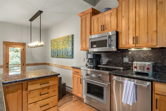 a kitchen with stainless steel appliances granite countertop a stove a sink and a microwave