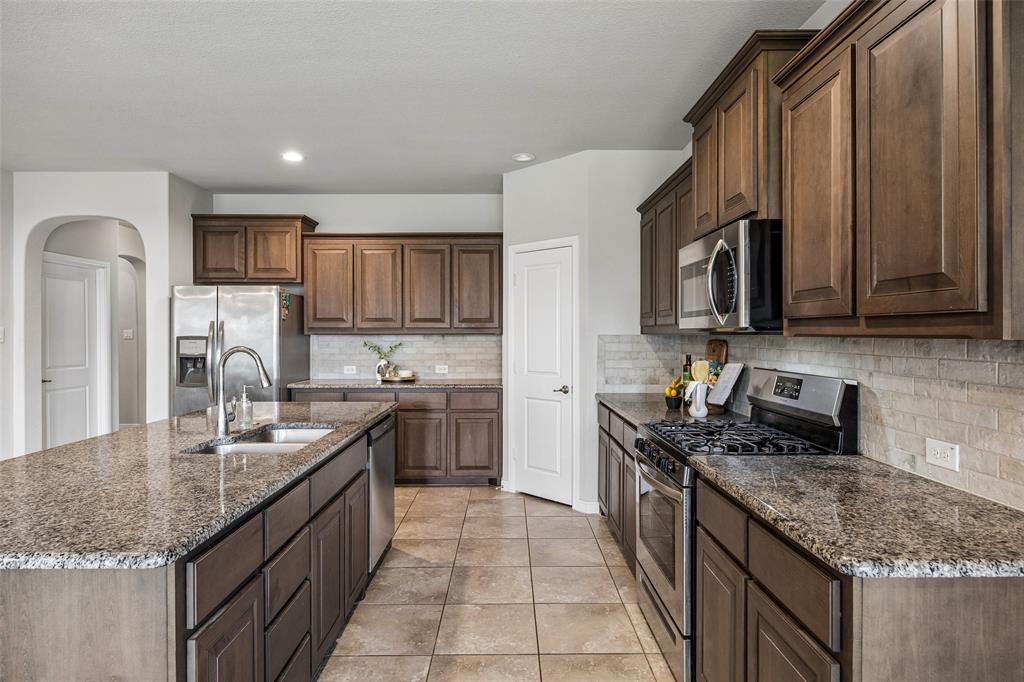 2508 Red Draw Road Fort Worth, TX 76177 - Photo 7 of 38 Spacious kitchen with granite countertops, stainless steel appliances, dark wood cabinetry, tile flooring, and a subway tile backsplash