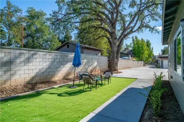 a view of a backyard with table and chairs and a large tree