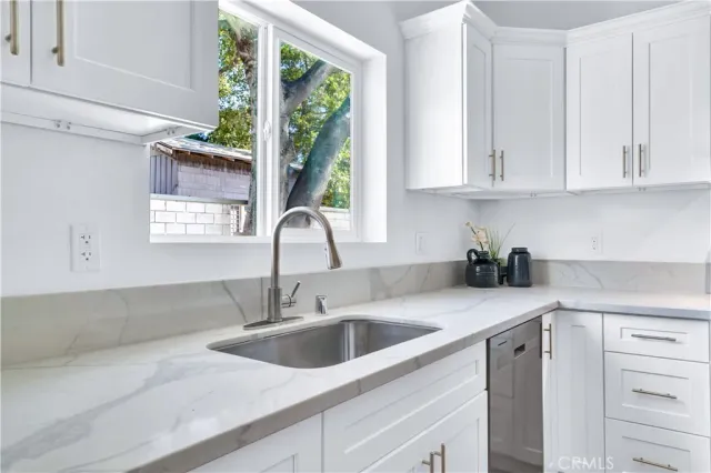a kitchen with stainless steel appliances granite countertop a sink a window and cabinets