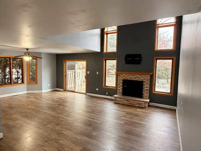 an empty room with wooden floor a fireplace and windows
