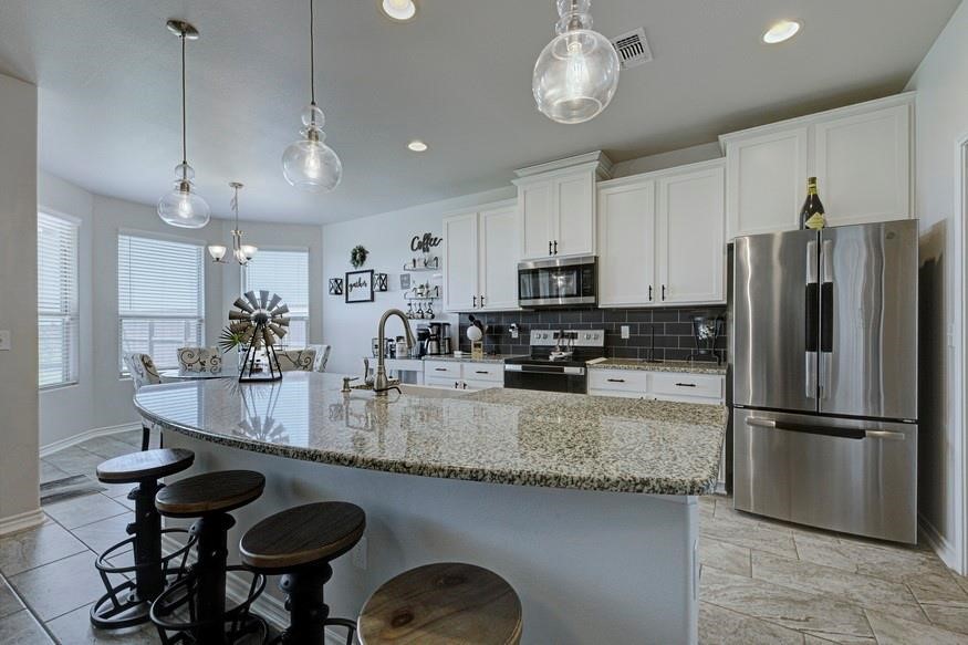 1007 Ocean Breeze Portland, TX 78374 - Photo 7 of 17 a kitchen with kitchen island granite countertop stainless steel appliances a sink a stove a refrigerator cabinets and chairs