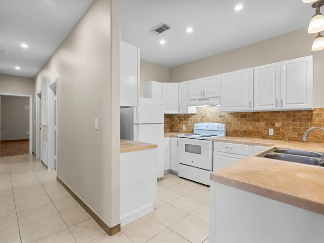 a kitchen with granite countertop a refrigerator and white cabinets