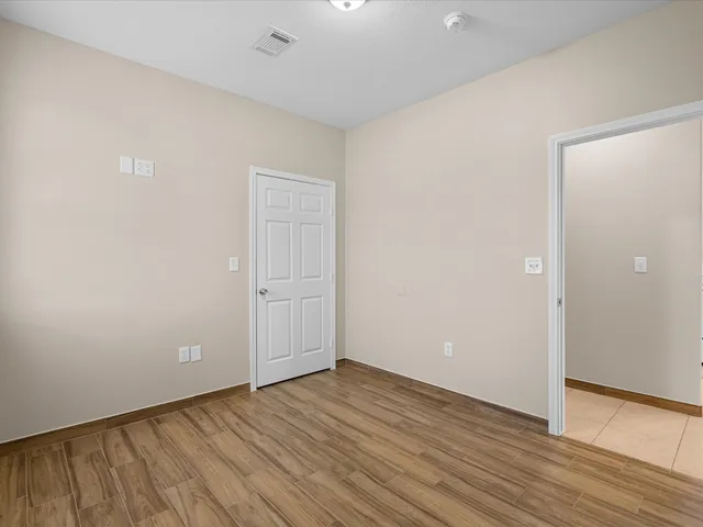 a view of an empty room with wooden floor and closet