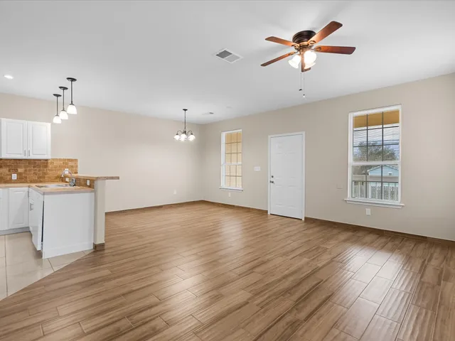 a view of an empty room with window and wooden floor