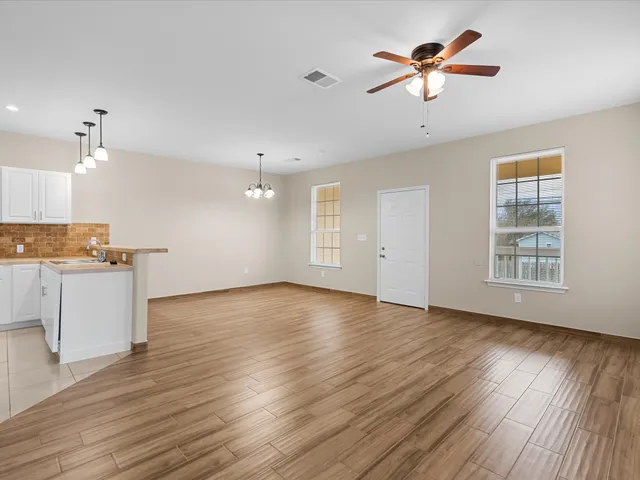 a view of an empty room with window and wooden floor