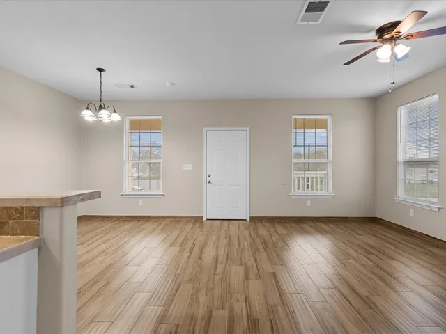 a view of an empty room with a window and wooden floor