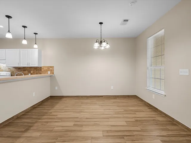 a view of a room with wooden floor and kitchen