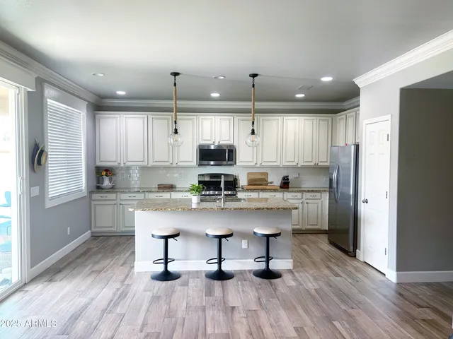 a kitchen with stainless steel appliances granite countertop a kitchen island hardwood floor sink stove and white cabinets